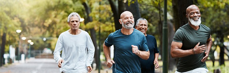 four fit, strong senior men running in a park