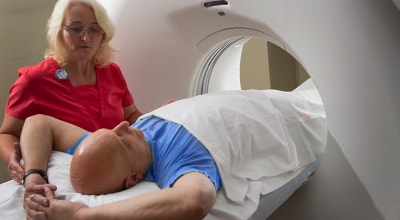 Member of Imaging and Radiology Services team speaking to patient about to go through imaging machine